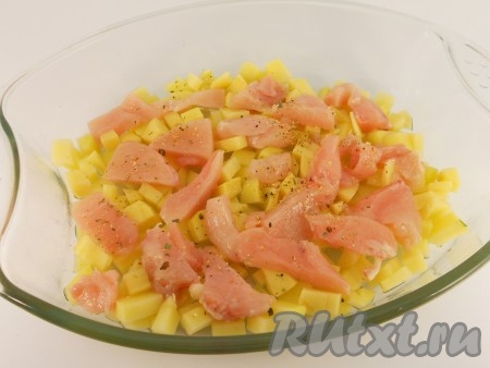 В форму для запекания влить растительное масло. Картофель очистить и порезать мелкими кубиками, выложить в форму. Сверху, на картофель поместить куриное филе, порезанное небольшими кусочками. Посолить и посыпать специями для курицы.