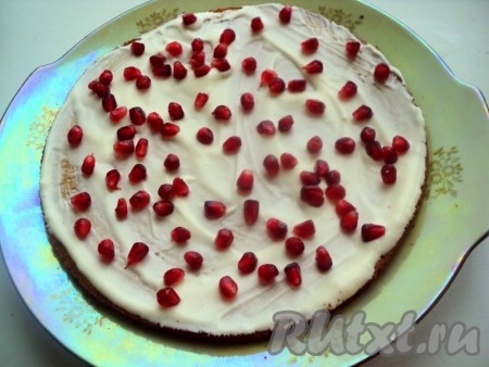 Гранат почистить и разобрать на зёрна. Смазать белый корж небольшим количеством сметанного крема, посыпать зёрнами граната.