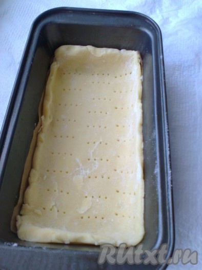 Через 2 часа достать тесто. Раскатать. Форму для выпечки смазать сливочным или растительным маслом (я застелила пекарской бумагой), выложить тесто в форму, разровнять и наколоть вилкой.
