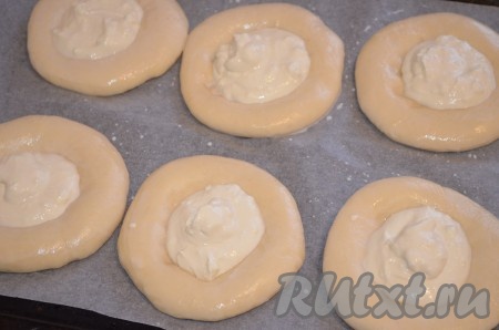 Затем смазать молоком края ватрушек из дрожжевого теста, выложить в углубление творожную начинку примерно по 2/3 столовой ложки.&nbsp;Поместить противень в заранее разогретую до 200-220 градусов духовку.&nbsp;
