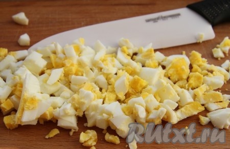 2 яйца выкладываем в кастрюльку с холодной водой, ставим на огонь, а после закипания отвариваем в течение 9-10 минут, затем остужаем их в холодной воде, очищаем и нарезаем на небольшие кубики.