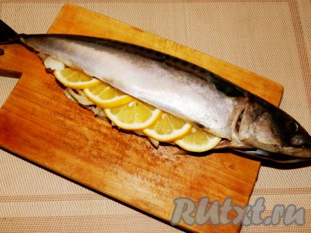 Скумбрию разморозить при комнатной температуре, тщательно вымыть, удалить внутренности и жабры, обсушить бумажным полотенцем. Натереть солью, перцем и оливковым маслом. Внутрь рыбы положить нарезанный лук, затем кусочки лимона. (Внутрь положить столько лука и лимона, сколько поместится, остальное добавим в рукав).
