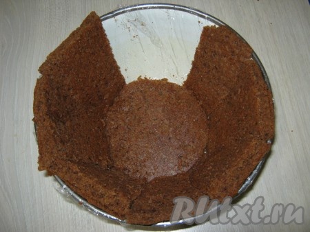 Чашу, с помощью которой мы вырезали круг, застилаем пищевой плёнкой. Оставшийся корж режем на треугольники (если у вас чаша с прямым дном, как у меня, то я сначала вырезала дно, а потом боковинки в виде прямоугольников, зауженных книзу чаши). Вырезанными кусочками выкладываем всю чашу. Если у вас получаются где-то щели, то их можно засыпать крошкой, оставшейся от коржа. Самое главное, чтобы вся чаша была закрыта (у меня на фото я еще не положила один кусочек).
