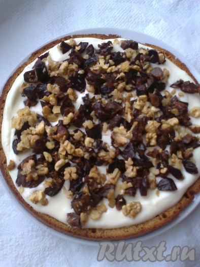 На подготовленное блюдо выложить корж и промазать его половиной крема. Сверху распределить половину измельченного чернослива с орехами. Тоже самое повторить со вторым коржом.
