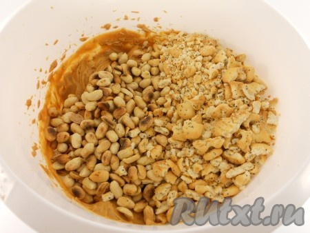 Взбить миксером масло со сгущёнкой до однородности. 3-4 столовые ложки получившегося крема из масла и сгущёнки отложить в небольшую ёмкость (этот крем потребуется для украшения торта). В крем из масла и сгущёнки, оставшийся в миске, выложить остывший арахис и поломанный крекер.