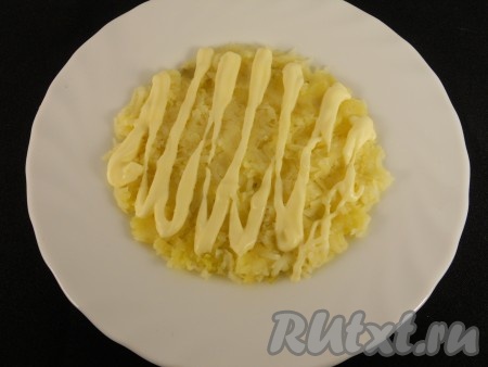 Картофель очистить и натереть на мелкой терке. Третью часть картофеля выложить в форме круга на блюдо. Немного посолить и смазать майонезом.