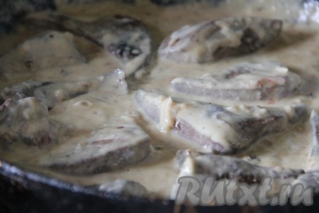 Затем выложить кусочки обжаренной говяжьей печени, перемешать, покрывая печёнку сметанным соусом со всех сторон, накрыть сковороду крышкой. Тушить с момента закипания соуса 15-20 минут на небольшом огне.