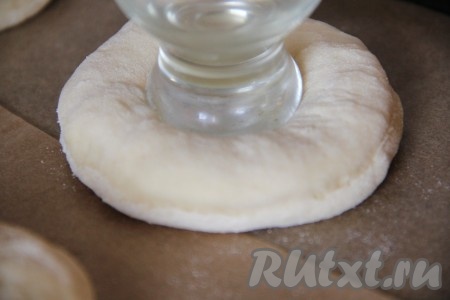 Подошедшее сдобное дрожжевое тесто на присыпанной мукой поверхности раскатать в пласт толщиной 1 сантиметр. С помощью кружки выдавить кружочки из теста (я выдавила 24 штуки - именно столько ватрушек у меня и получилось). Выложить их на противень, застеленный пергаментной бумагой, и оставить на 15 минут. По прошествии времени в серединке каждого кружочка из теста сделать углубление с помощью дна рюмочки.