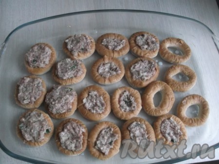 Форму смазываем маслом и выкладываем в неё сушки. Чайной ложкой раскладываем фарш.