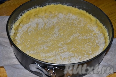 Дно формы диаметром 26 см застелить бумагой для выпечки, бока смазать маслом. Остальное тесто выложить в форму, формируя бортики. Присыпать тесто манкой.
