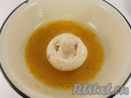 Яйца взбить вилкой с солью, черным молотым перцем и мускатным орехом. В глубокую сковороду влить растительное масло и разогреть. Масла должно быть достаточно, чтобы шампиньоны были наполовину погружены в него. Каждый грибок аккуратно окунуть внешней стороной в яичную смесь.