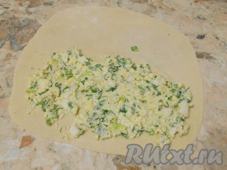 Тесто разделить на кусочки (размер зависит от диаметра сковороды). Я разделила тесто на 5 частей. Каждую часть теста скатать в шарик. Каждый шарик на присыпанном мукой столе раскатать в тонкую лепёшку. Начинку зрительно разделить на 5 частей. На половину лепёшки, немного отступая от краёв теста, равномерно выложить начинку из творога и зелени, как на фото.