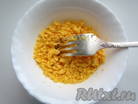 Желтки выложить в глубокую тарелку, размять вилкой.