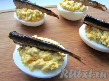 Поверх каждого фаршированного яйца выложить шпротинку.