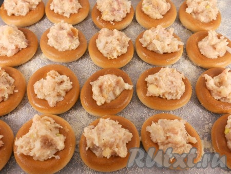 Противень застелить пергаментной бумагой, смазать растительным маслом и посыпать манной крупой. Выложить подготовленные бублики. Отверстие начинить фаршем.