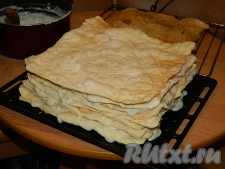 Откладываем в сторону самый румяный корж, мы его будем в дальнейшем измельчать и использовать для заключительной посыпки. Смазываем коржи хорошенько кремом (крема не жалеем). Немного крема оставляем на финальную обмазку торта (после остывания этот крем можно накрыть и убрать в холодильник). Чтобы крем не вытекал с боков, а хорошо их пропитал, - жать на коржи, смазанные кремом, не надо, просто нужно их плотно выкладывать друг на друга. Самый последний (верхний) корж из слоёного теста заварным кремом не смазываем. Оставляем торт на 3-4 часа пропитываться при комнатной температуре. Но я делала вечером, поэтому убрала торт "Наполеон" на всю ночь в холодильник.