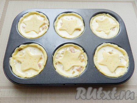 Залить заливкой, примерно по 2-3 столовые ложки на одну форму, сверху разложить звездочки из теста и поставить в разогретую до 180 градусов духовку на 25 минут.