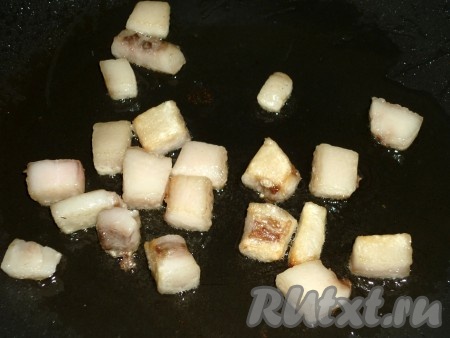 Куриную печено промыть, обсушить. Сало нарезать на небольшие кусочки и отправить на сковороду, обжарить на среднем огне до лёгкого подрумянивания со всех сторон.