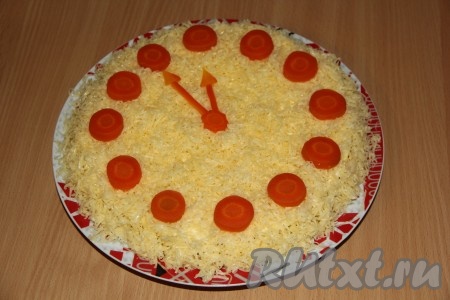 Морковь почистить, нарезать ровные, тонкие кружочки и сделать стрелку для часов. Выложить кружочки и стрелки на салат.