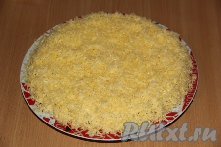  Сыр натереть на мелкой тёрке. Аккуратно снять бортики с салата. Покрыть салат щедрым слоем сыра.