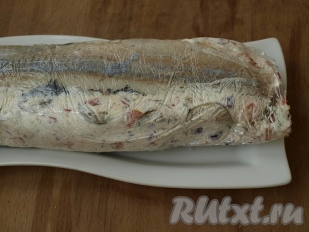 Желатин заливаем водой и ставим на водяную баню до полного растворения. Слегка остывший желатин смешиваем со сметаной. В получившуюся сметанно-желатиновую смесь добавляем порезанные овощи, немного лимонного сока, солим и перчим. На пищевую плёнку выкладываем одну часть филе, на неё размещаем половину сметанно-желатиновой массы с овощами, пластины огурца. Сверху выкладываем вторую половину сметанно-желатиновой массы и накрываем второй частью филе сельди.
