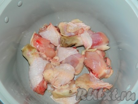 Наливаем немного растительного масла на дно чаши мультиварки. Режем курицу и выкладываем на дно мультиварки.
