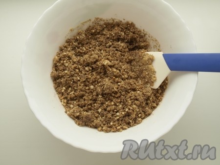 Сливочное масло растапливаем, даём немного остыть. Печенье, измельчённое в крошку, смешиваем с растопленным маслом, тщательно перемешиваем.