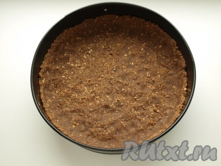 Форму для выпечки застилаем пекарской бумагой, выкладываем получившуюся смесь из печенья и масла, аккуратно разравниваем, формируя бортики, и ставим в холодильник.