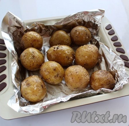 Смешать растительное масло с солью и чёрным молотым перцем. В подходящую форму для запекания выложить картофель. Я дополнительно застелила форму фольгой, но это необязательно. Каждый клубень обмазать масляной смесью. Духовку разогреть до 200 градусов и поставить картошку запекаться.