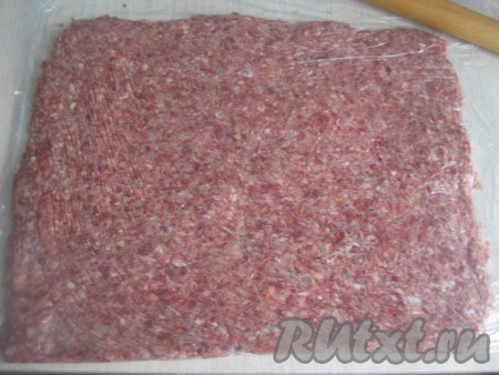 Теперь фарш накрываем другой частью плёнки и с помощью скалки раскатываем толщиной 1-1,5 см.
