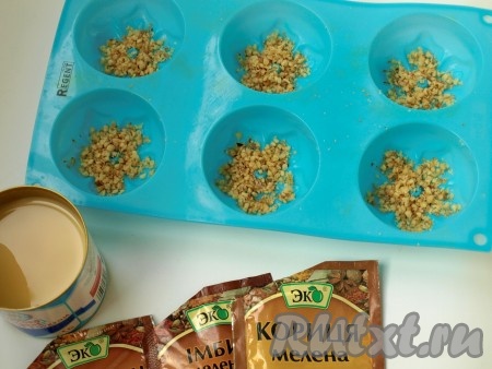 На дно силиконовых формочек кладём немного измельчённых орешков.