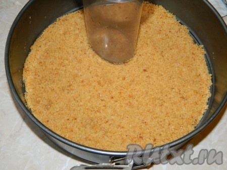 Сухари измельчить и смешать с мягким сливочным маслом. Полученную массу выложить в разъемную форму, утрамбовать, разровнять, например, стаканом.
