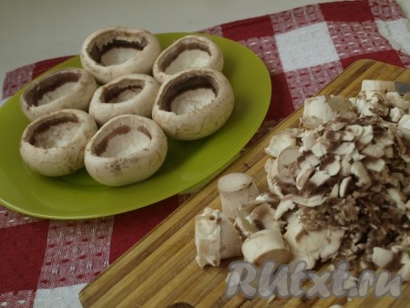 Шампиньоны тщательно моем, отделяем ножку и вычищаем шляпку, чтобы получились вместительные чашечки. Половину оставшейся грибной массы, включая ножки, мелко режем.
