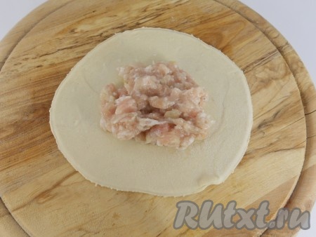 Нарезать тесто на кусочки приблизительно по 40-50 грамм, скатать в шарики. Раскатать скалкой тонкие лепешки и с помощью блюдца обрезать ровно края. Диаметр лепешки для хинкали должен быть около 15 см. Поместить в центр 1-2 столовые ложки подготовленного фарша.
