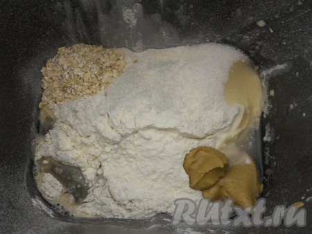 В ведерко хлебопечки влить теплую воду, всыпать просеянную смесь из муки. По углам разместить соль, сахар, овсяные хлопья, горчицу, влить растительное масло. Если по инструкции к вашей хлебопечке нужно загружать продукты в ином порядке - так и делайте!