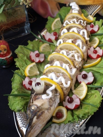 Фаршированную щуку достаём из духовки, полностью охлаждаем, потом разворачиваем фольгу и нарезаем рыбку на порционные кусочки. Перекладываем наивкуснейшую щуку на блюдо, украшаем лимоном и овощами.
