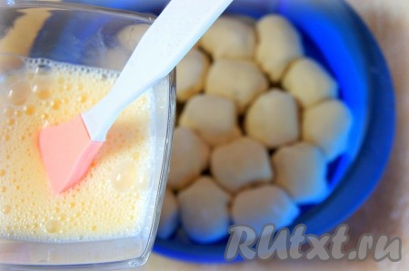 Яйцо взбить вилкой. С помощью кондитерской кисти тщательно обмазать булочки взбитым яйцом.