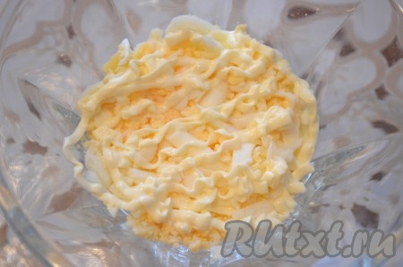 В салатник выложить первым слоем яйца. Посолить и поперчить по желанию, смазать сметаной или майонезом.
