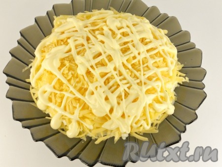 Равномерно покрываем салат сверху и по бокам сыром, натёртым на крупной тёрке, смазываем майонезом.