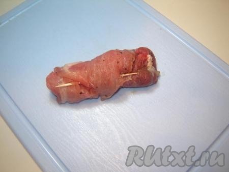Осторожно заворачиваем нашу начинку в мясо, чтобы получился рулетик. Закрепляем деревянными шпажками или зубочистками конец мяса.