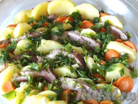 Смазываем сливочным маслом форму для запекания. Выкладываем вертикально слоями картофель, морковь и свинину. Сверху посыпаем порезанной петрушкой и зелёным луком.
