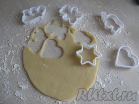 Посыпаем стол мукой и небольшими порциями раскатываем тесто толщиной примерно 5 мм. Выдавливаем формочками фигурки.