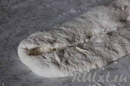 Подошедшее тесто обмять и на присыпанной мукой поверхности растянуть тесто руками в прямоугольник. Загнуть один край теста к центру прямоугольника.