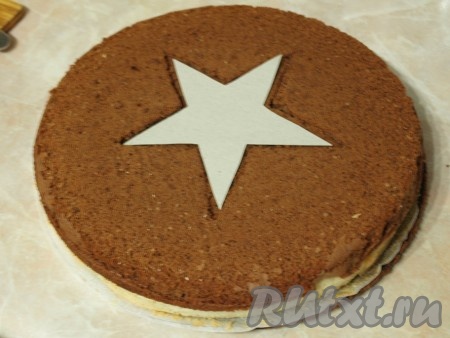 На белый корж положить один шоколадный корж и с помощью шаблона в середине этих двух коржей вырезать звезду. Из белой и шоколадной звёздочек, вырезанных из коржей, я приготовила пирожное, промазав звездочки кремом.
