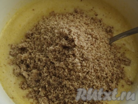 150 грамм грецких орехов перемалываем в крошку и добавляем к смеси сметаны и яиц, перемешиваем.