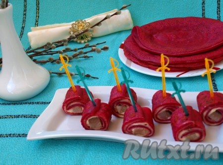 Режем свекольные блины на рулетики и скрепляем шпажками. Закуска из блинчиков получается не только оригинальной, но и вкусной.
