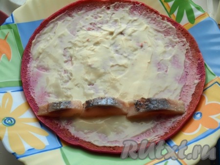 Выкладываем в ряд (можно слегка внахлёст) кусочки сельди.
