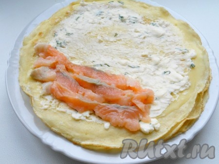 Смазать блинчики подготовленным сыром. На одну половину блинчика выложить кусочки семги.