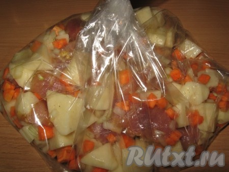 Затем картошку с овощами и свининой выложить в рукав для запекания. Плотно завязать рукав с двух сторон. На дно глубокого противня (или в формы для запекания) налить немного воды, затем выложить рукав с мясом и овощами. На поверхности рукава сделать несколько проколов иголкой, чтобы он не вздувался при запекании. Отправить в разогретую духовку и готовить 1 час при температуре 180 градусов.