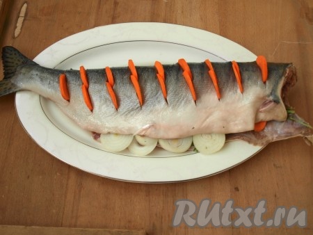 На поверхности горбуши делаем надрезы и помещаем в них тонко нарезанную морковь. Внутрь тоже можно положить несколько кружков моркови.
